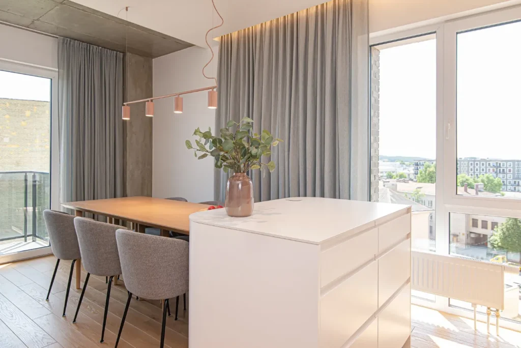 Valgomojo zona su pilkomis kėdėmis ir miesto panorama pro langą