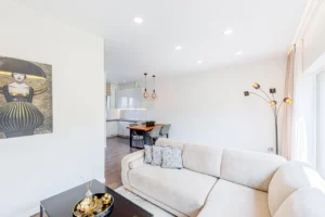 Valgomojo zona su mediniu stalu, moderniu šviestuvu ir šviesiomis sienomis