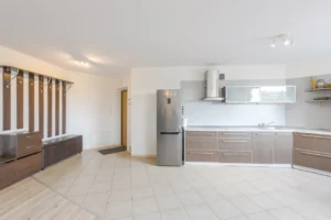 Virtuvės erdvė su baltomis ir rudomis spintelėmis bei nerūdijančio plieno šaldytuvu