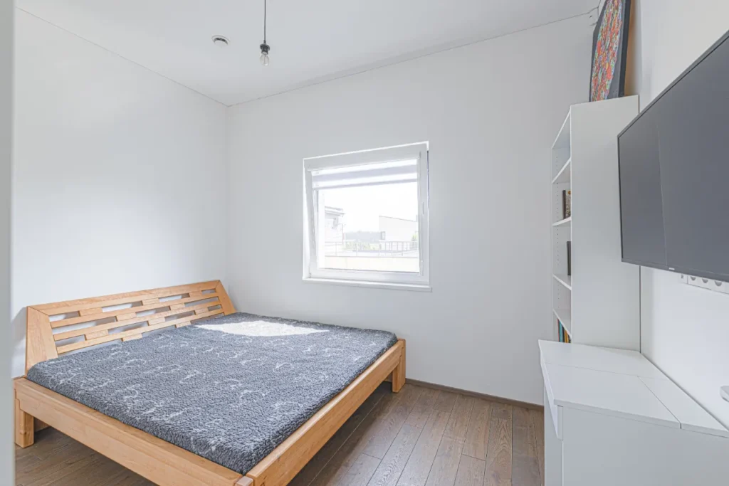 Vaiko ar svečių kambarys su viengule lova, lentynomis ir langu