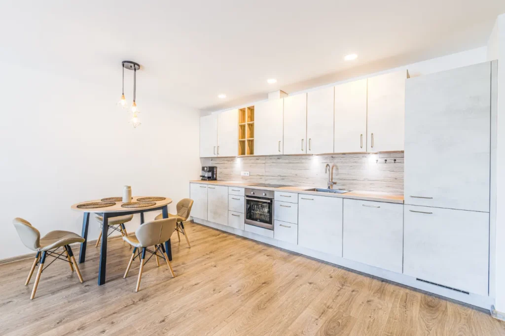 Moderni balta virtuvė su integruota technika ir apvaliu valgomojo stalu