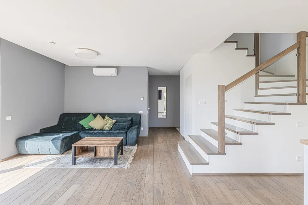 Svetainė su moderniais laiptais ir pilka siena – šiuolaikinis interjeras